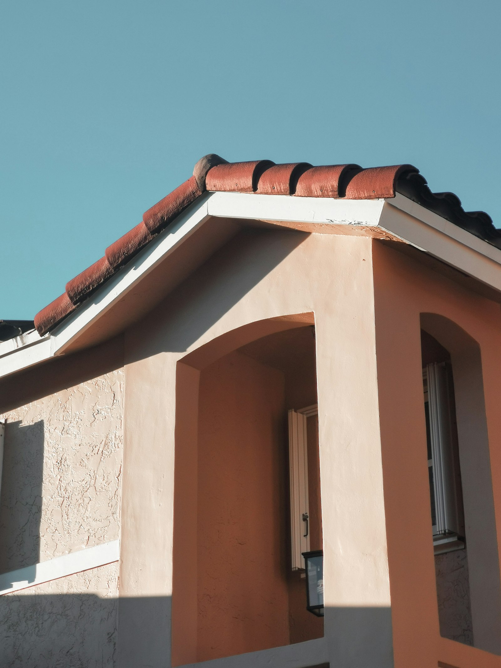 Sunlit tile roof eave against a clear blue sky. TODO: replace with a Bill Ragan skylight photo.